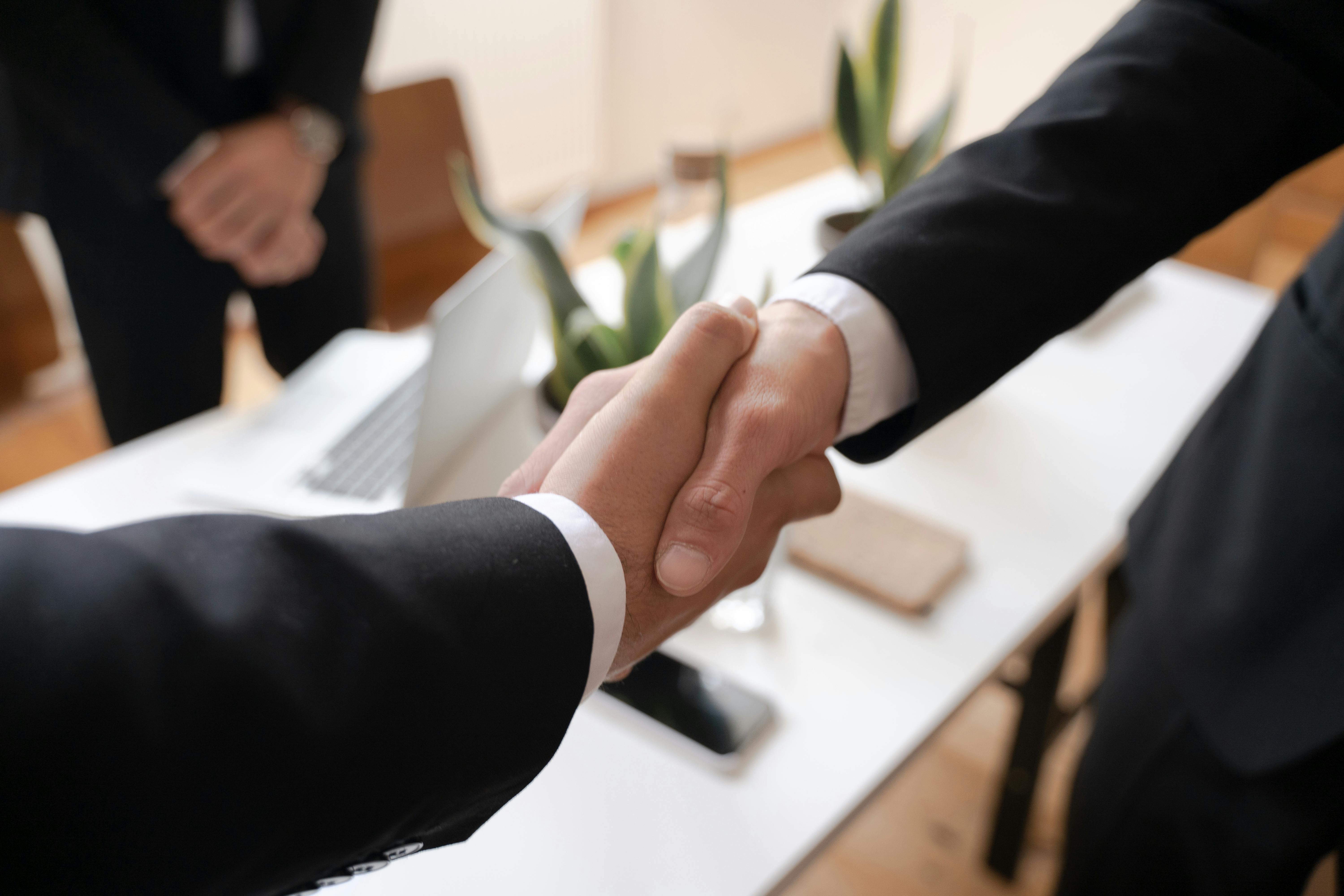 Two business people shaking hands over a clean desk.